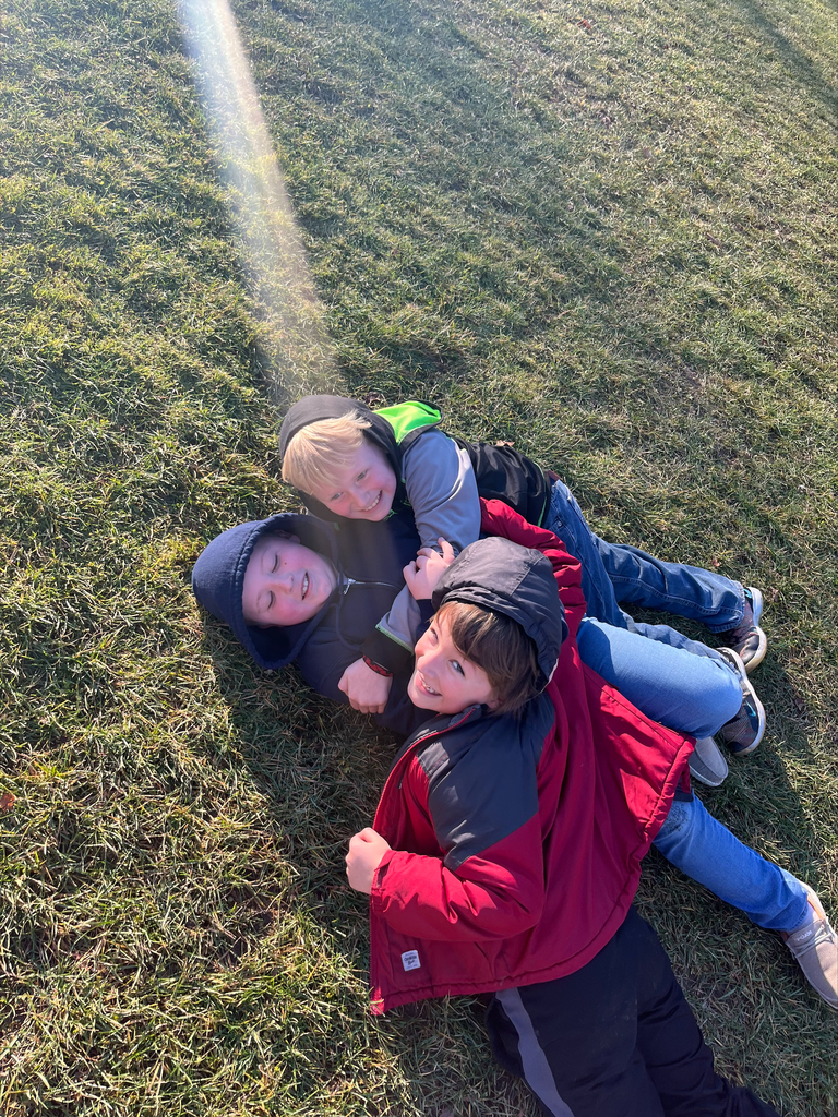 4th-grade students playing in the grass.